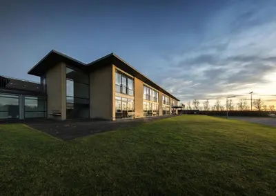 a building with a grass field in front of it at Jetsmark Idrætscenter in Pandrup