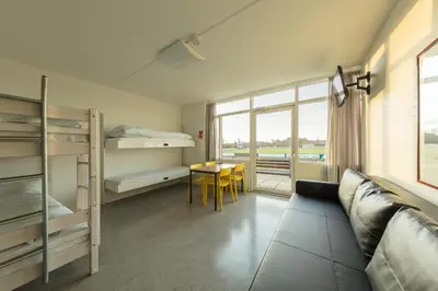 a room with bunk beds and a table and a couch at Jetsmark Idrætscenter in Pandrup