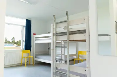 a bunk bed in a room with two chairs and a ladder at Jetsmark Idrætscenter in Pandrup