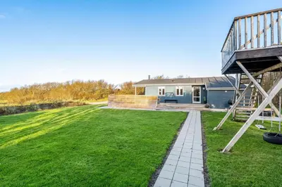 a house with a large yard with a staircase at Beautiful Holiday Home With A Lovely View Of The Fjord And The Sea in Vestervig