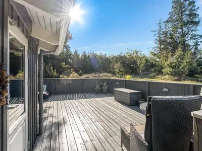 a wooden deck with two chairs on a house at Holiday Home Elisenda - 2-2km from the sea by Interhome in Blokhus