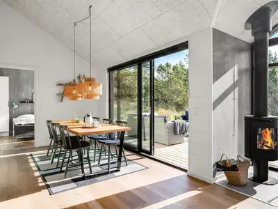 a dining room with a table and chairs and a fireplace at Holiday Home Helga - 900m from the sea by Interhome in Blokhus