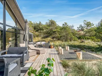 a patio with chairs and tables on a wooden deck at Holiday Home Helga - 900m from the sea by Interhome in Blokhus