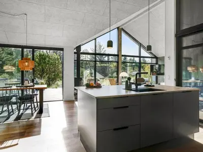 a kitchen with large windows and a dining room with a table at Holiday Home Helga - 900m from the sea by Interhome in Blokhus