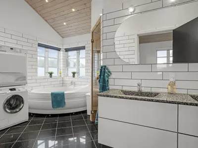 a bathroom with a tub and a sink and a washing machine at Holiday Home Djuna - 550m from the sea by Interhome in Saltum