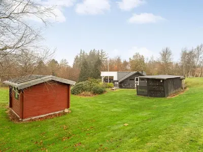 two smallsheds in a grassy field in front of a house at Holiday Home Jantje - 500m to the fjord by Interhome in Spottrup