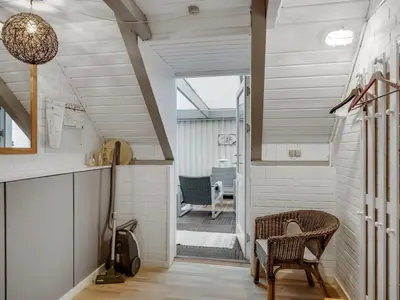 a room with a staircase with a chair and a table at Holiday Home Amina - 50m from the sea by Interhome in Torsted