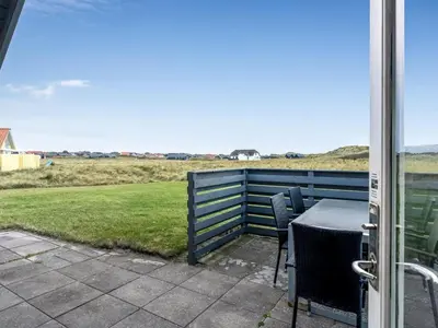 a table and chairs on a patio with a view of a field at Holiday Home Amina - 50m from the sea by Interhome in Torsted