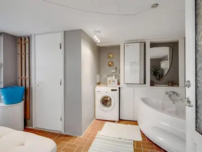 a bathroom with a tub and a washing machine at Holiday Home Amina - 50m from the sea by Interhome in Torsted