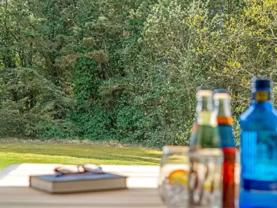 a table with a bottle and a book and a drink at Holiday Home Star - 600m from the sea by Interhome in Løkken