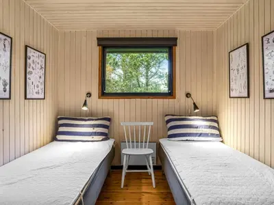 two beds in a room with a table and a window at Holiday Home Star - 600m from the sea by Interhome in Løkken
