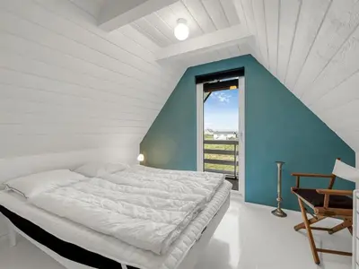 a bedroom with a white bed and a blue wall at Holiday Home Kaja - 150m from the sea by Interhome in Harboør