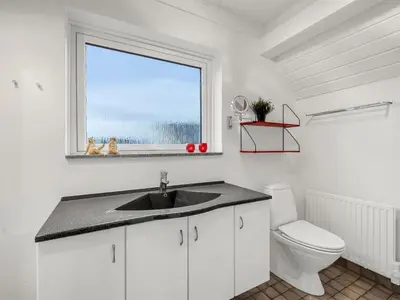 a bathroom with a sink and a toilet and a window at Holiday Home Kaja - 150m from the sea by Interhome in Harboør