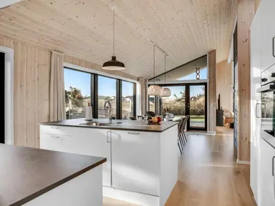 a kitchen with white cabinets and a large window at Holiday Home Godja - 300m from the sea by Interhome in Torsted