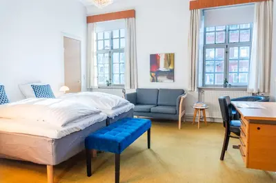 a bedroom with a bed and a couch and a desk at Cityinn Hotel in Viborg