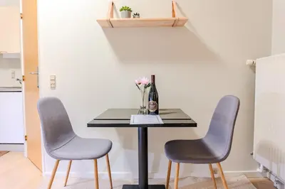 a table with two chairs and a vase of flowers at Villa Apartments Viborg in Viborg