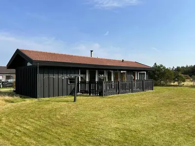 a black house with a fence in front of it at Architect-Designed Summer House In Agger in Vestervig