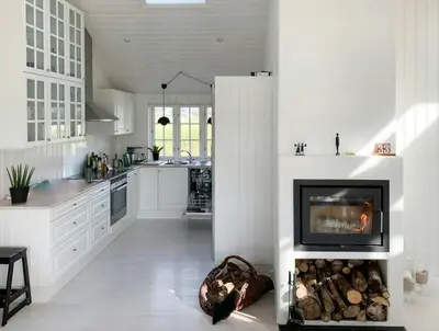 a white kitchen with a fireplace in the middle at Home With Sauna Near Klitmøller in Thisted