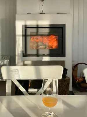 a glass of wine sitting on a table in front of a fireplace at Home With Sauna Near Klitmøller in Thisted