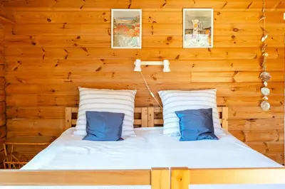 a bed in a wooden room with two blue pillows at North Jutland Nature Near Thorup Beach in Fjerritslev