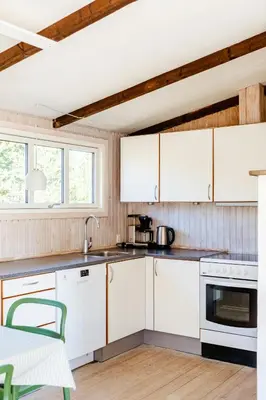 a kitchen with white cabinets and a sink and a table at North Jutland Nature Near Thorup Beach in Fjerritslev