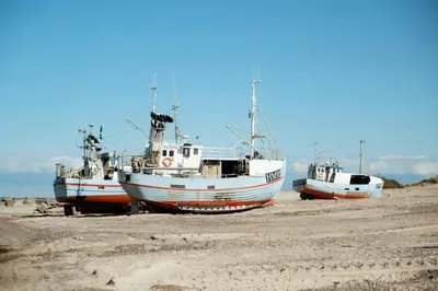 three boats sitting on the sand on the beach at North Jutland Nature Near Thorup Beach in Fjerritslev
