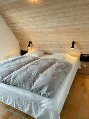 a large white bed in a room with wooden walls at Architect-Designed Gem At The West Coast in Pandrup