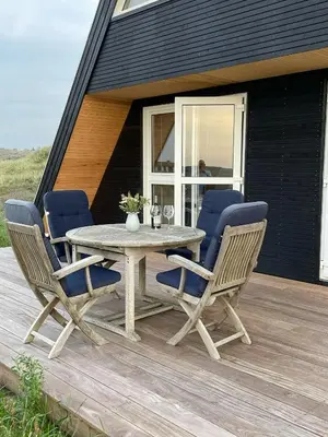 a wooden table and chairs on a wooden deck at Architect-Designed Gem At The West Coast in Pandrup