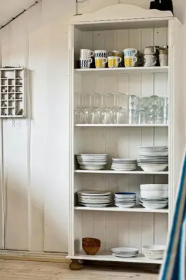 a white cabinet filled with plates and bowls at Home By Limfjord Where Sea And Sky Meet in Hurup
