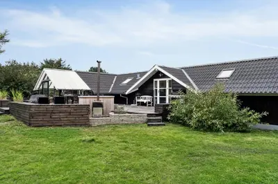 a house with a black roof and a yard at Home By Limfjord Where Sea And Sky Meet in Hurup