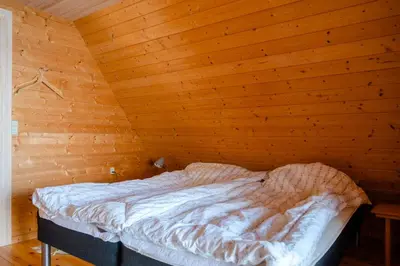 a bed in a room with a wooden wall at Nature Gem 5 Metres From Limfjord in Roslev