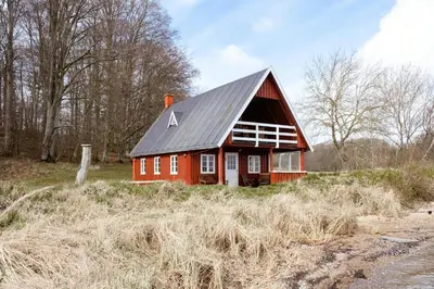 a red barn with a black roof on a field at Nature Gem 5 Metres From Limfjord in Roslev