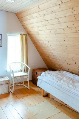 a bedroom with a wooden ceiling with a bed and a chair at Nature Gem 5 Metres From Limfjord in Roslev