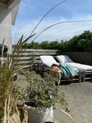 a person laying on a patio with two beds at Cozy Summer House In Agger Near The North Sea in Vestervig