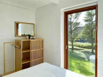 a bedroom with a mirror and a window at Cozy Summer House In Agger Near The North Sea in Vestervig