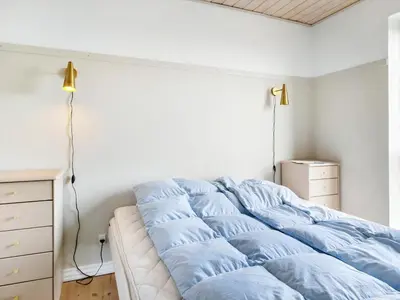 a bed with blue sheets on it in a bedroom at Summer House With Panoramic View Near Doverodde in Doverodde