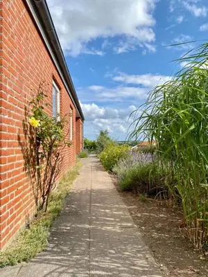 a sidewalk next to a brick building with a field of flowers at Summer House With Panoramic View Near Doverodde in Doverodde