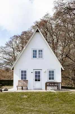 a white house with two benches in front of it at Small House With View Of The Limfjord in Roslev