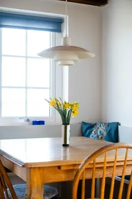 a dining room table with a vase of flowers on it at Small House With View Of The Limfjord in Roslev