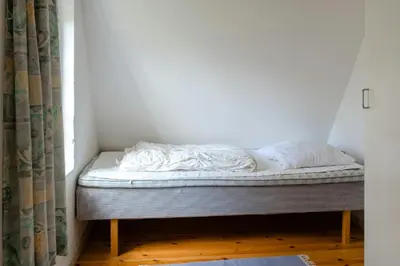 a bed sitting in a room with a window at Small House With View Of The Limfjord in Roslev