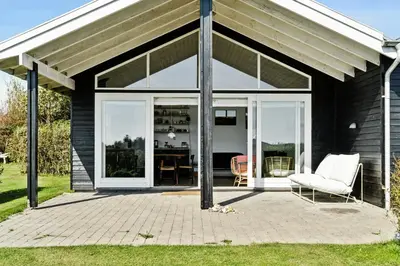 a screened in porch with a white couch and chairs at Cozy Home By Limfjord With Bathing Jetty in Snedsted