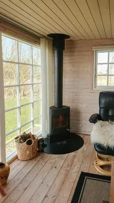 a woodburning stove in a room in a cabin at Charming Wooden Cottage Close To Handbjerg Beach in Vinderup