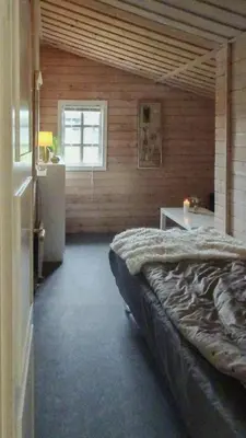 a bedroom with a bed and a table and a window at Charming Wooden Cottage Close To Handbjerg Beach in Vinderup