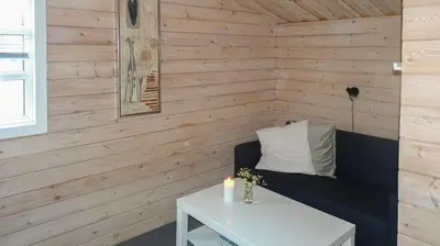 a room with a bench and a table with a candle at Charming Wooden Cottage Close To Handbjerg Beach in Vinderup