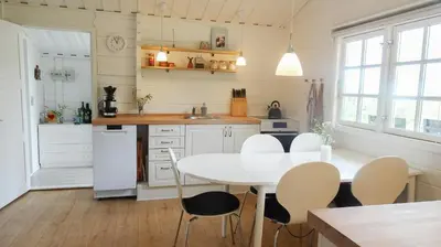 a white kitchen with a white table and chairs at Charming Wooden Cottage Close To Handbjerg Beach in Vinderup