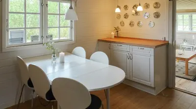 a kitchen with a white table and white chairs at Charming Wooden Cottage Close To Handbjerg Beach in Vinderup