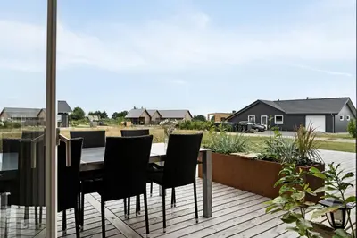 a wooden deck with a table and chairs on it at Modern Light House With Terrace Near The Fjord in Løgstrup