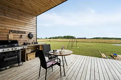a patio with a table and a stove and a field at Modern Light House With Terrace Near The Fjord in Løgstrup