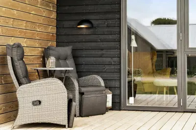 a patio with two chairs and a table and a window at Modern Light House With Terrace Near The Fjord in Løgstrup