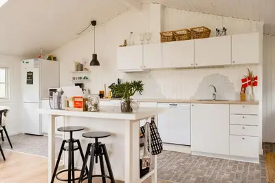 a kitchen with white cabinets and bar stools at Bright And Lovely Summerhouse In Løkken in Løkken